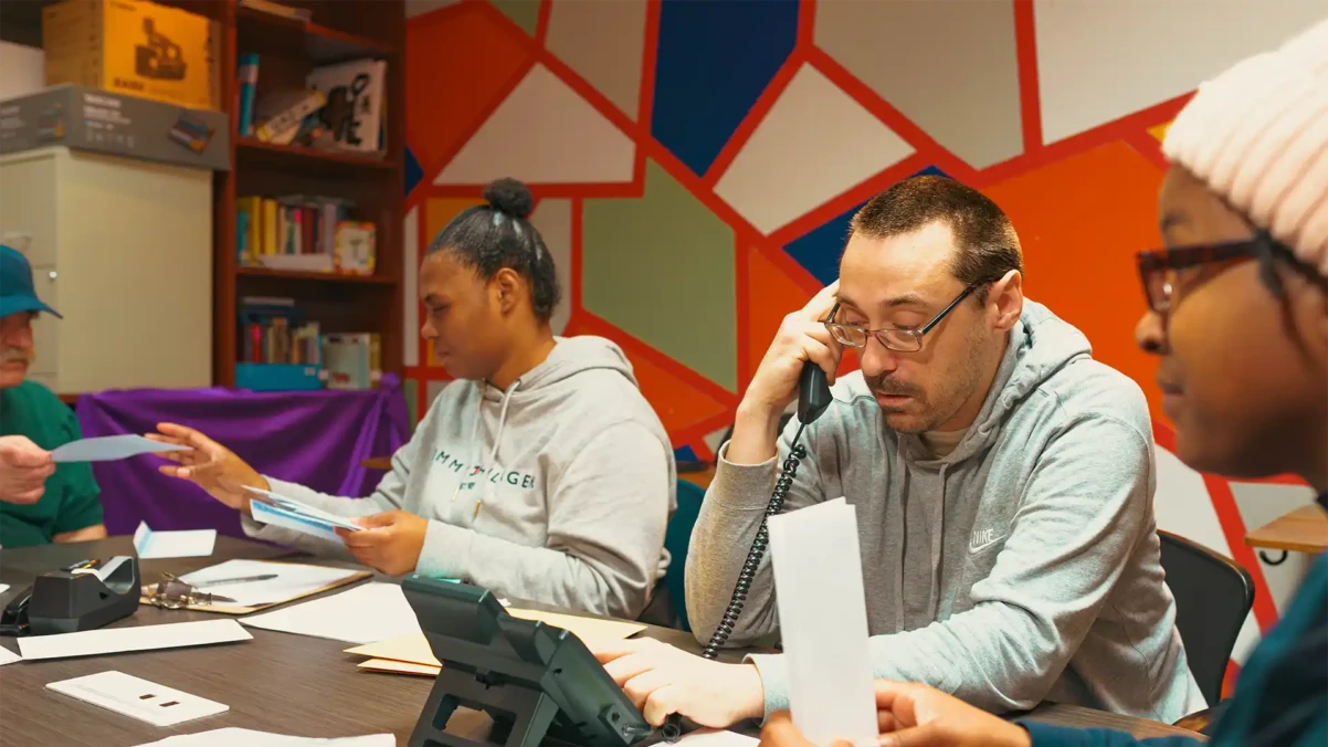 Venture House members sitting at a table working together with one on the phone