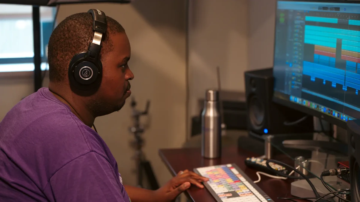 A man wearing headphones editing a video.